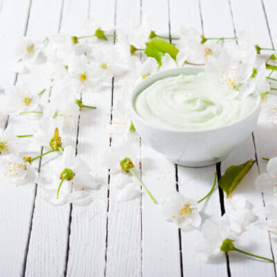 Cosmetic cream and cherry flowers on white wood table background