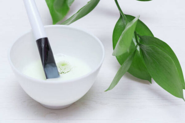 Natural cosmetic face mask in a jar on a white table background.