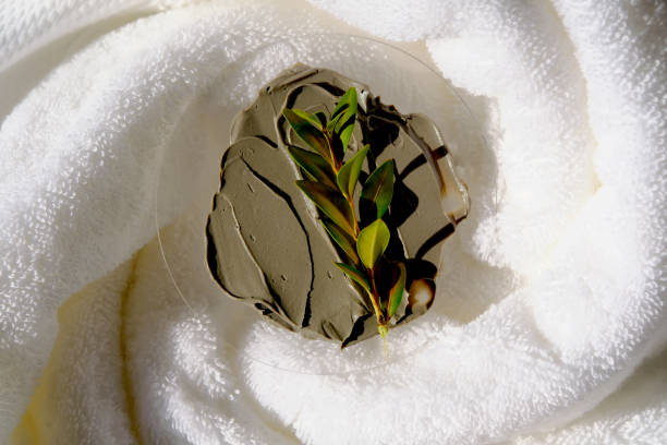 A sample of a mud mask on a terry bath towel with a green sprig.